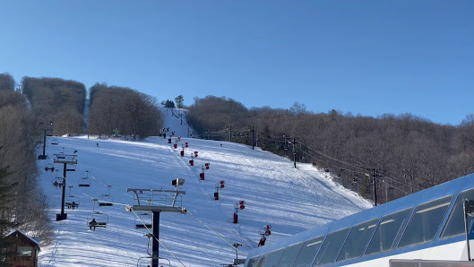 Winter sports scene at Bristol Mountain Ski Resort, New York, featuring a skier sliding down the snow-covered slopes amidst stunning winter scenery.
