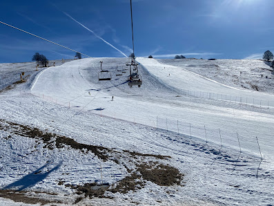 Winter scene at Forni di Sopra ski resort in Italy, featuring a chalet and a ski lift amidst the snow-covered slopes for winter sports activities.