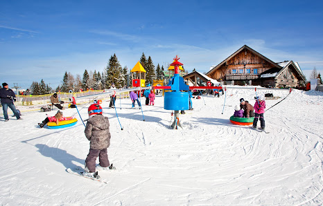 A scenic view of a winter sports scene at Cerkno ski resort in Gorenjska Slovenia featuring a ski lift a ski resort and a charming chalet amidst the snow-coated landscape.