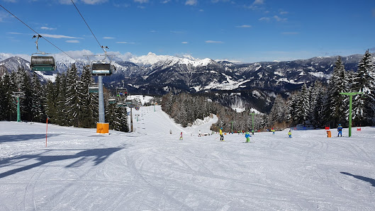 Winter scene at Cerkno ski resort in Slovenia, featuring a ski lift and a chalet. Skiers can be seen enjoying the snow-covered slopes.