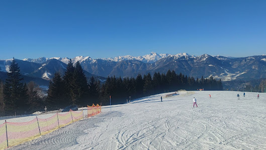 A scenic view of the ski resort in Cerkno, Gorenjska, Slovenia, featuring a charming chalet amidst landscapes of crisp snow, capturing a bustling winter sports scene.