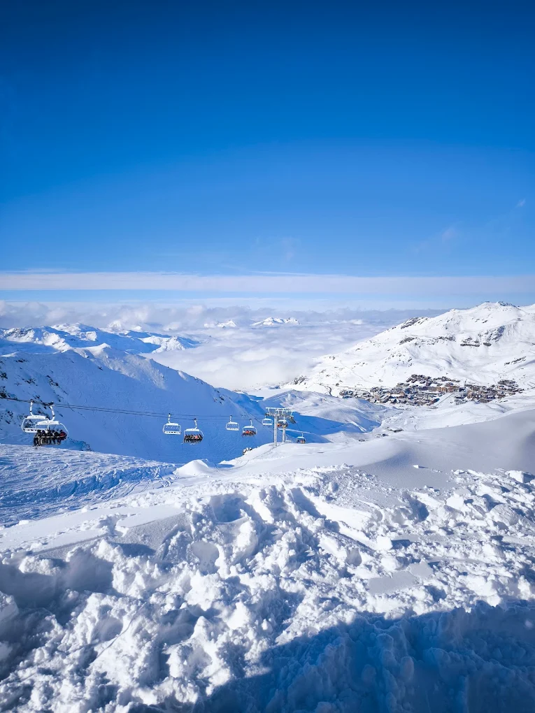 A skier enjoys a winter sports scene on the slopes of Les 3 Vallées, a ski resort in Savoie Mont Blanc, Auvergne-Rhône-Alpes, France, with a glimpse of a ski lift in the backdrop.