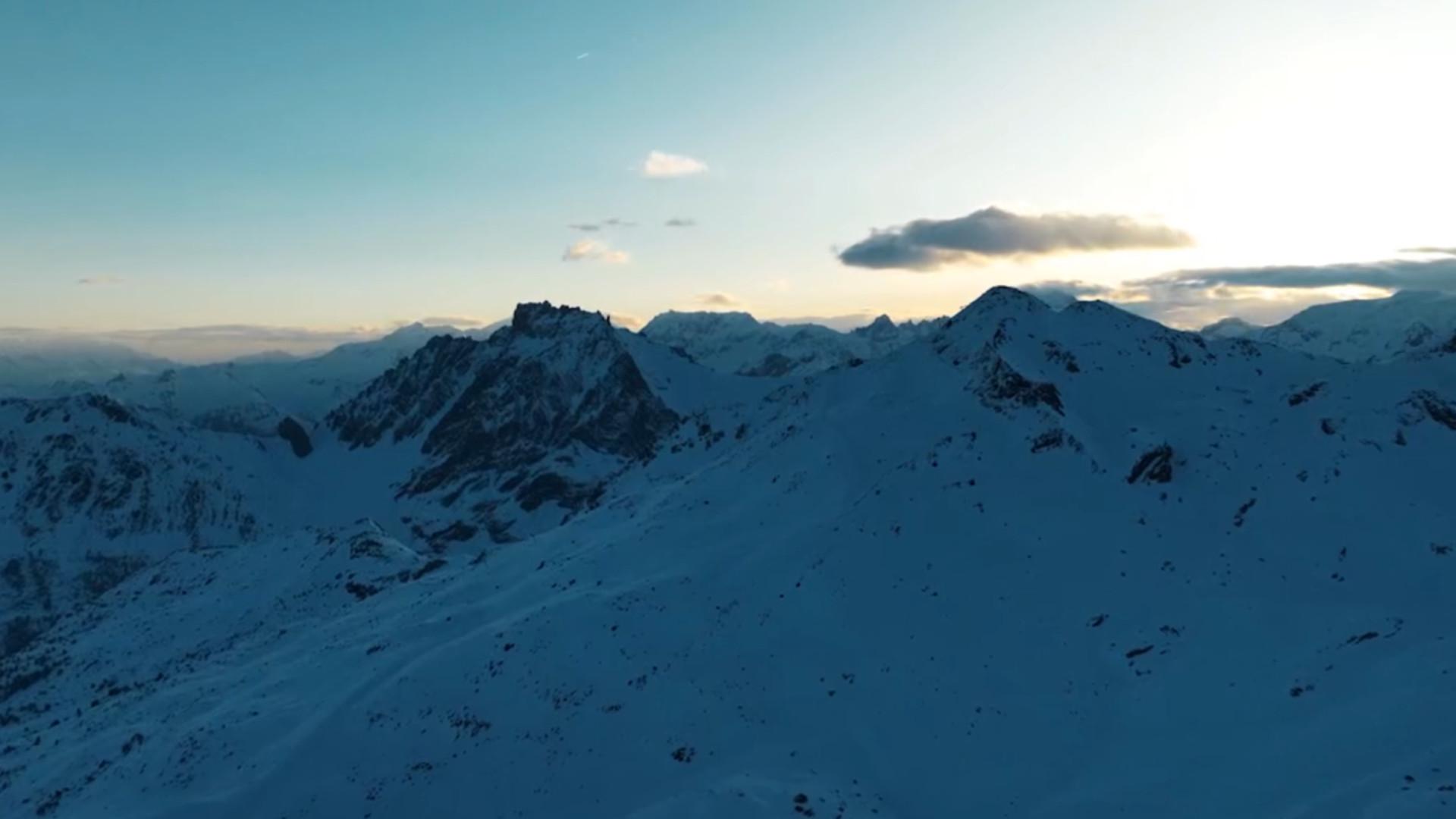 A skier in action at the Les 3 Vallées ski resort in Savoie Mont Blanc, France, with a stunning backdrop of snow-covered mountains.
