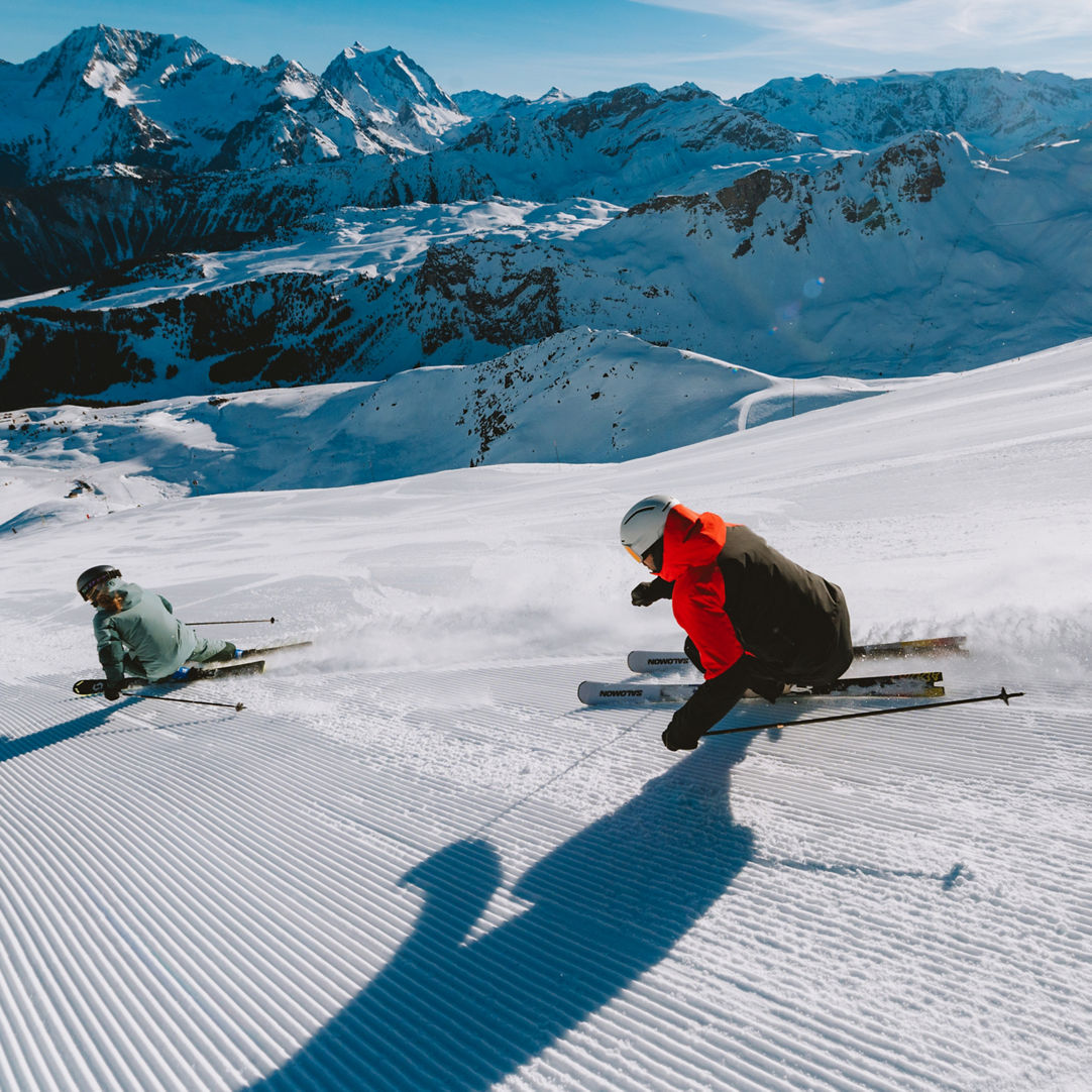 Les 3 Vallées in France - two people skiing down a snow covered mountain.