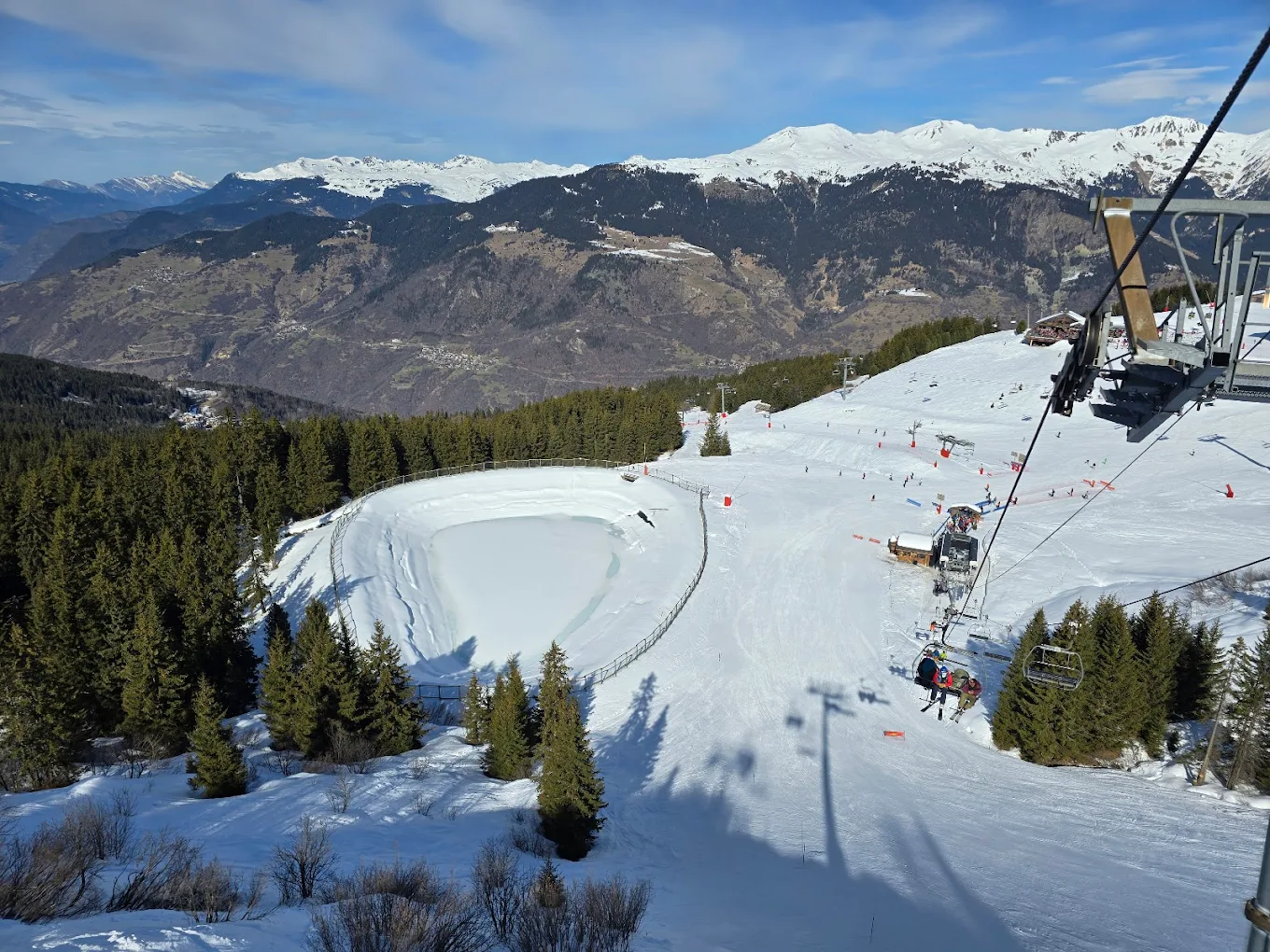 A skier swiftly gliding down the snow-covered slopes at Les 3 Vallées in France, with a cozy chalet in the near distance, amidst a vibrant winter sports scene.