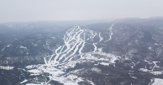 Winter scene at Mont Edouard ski resort in Quebec, featuring a skier navigating the snow-covered slopes amidst a beautiful winter landscape.