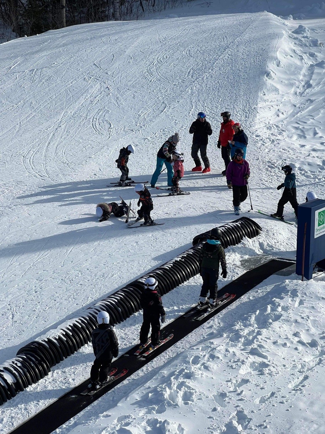 Winter sports scene at Mont Edouard Ski Resort in Quebec showing a ski lift a family skiing and a skier enjoying the serene snow-covered landscape.