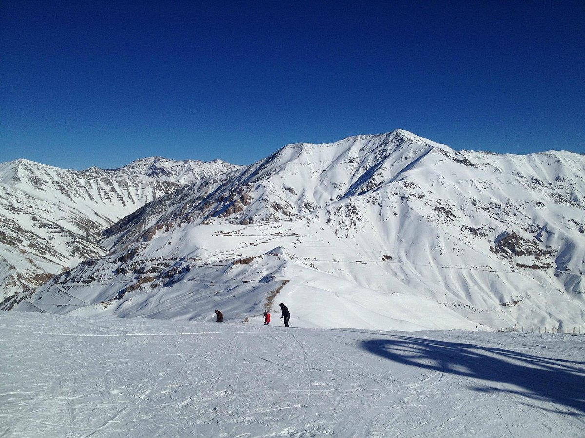 Dizin International in Iran - a person standing on top of a snowy mountain.