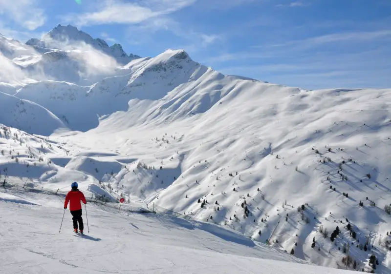 A dynamic winter sports scene at Cima Piazzi San Colombano in Valtellina Italy featuring a skier in action near a charming chalet all set against the backdrop of a bustling ski resort.