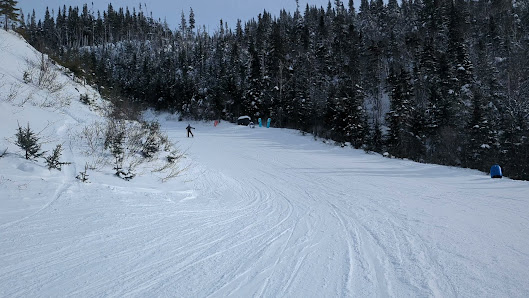 A skier enjoying a winter sports scene at Marble Mountain in Steady Brook, Newfoundland and Labrador, Canada, with a ski resort and ski lift in the backdrop.