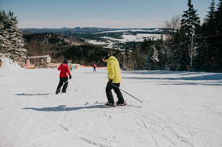 Winter sports scene at Mont Orignal in Quebec, Canada featuring a skier enjoying the slopes at a ski resort, surrounded by fellow ski enthusiasts.