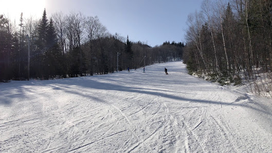 Skier descending the snowy slopes at Mont Orignal ski resort in Quebec Canada. Visible elements include a ski lift a chalet in the background and the stunning winter landscape.