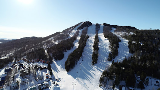 View of Mont Orignal Ski Resort in Quebec, Canada, complete with ski lifts, bustling with winter sports enthusiasts on snow-covered slopes.
