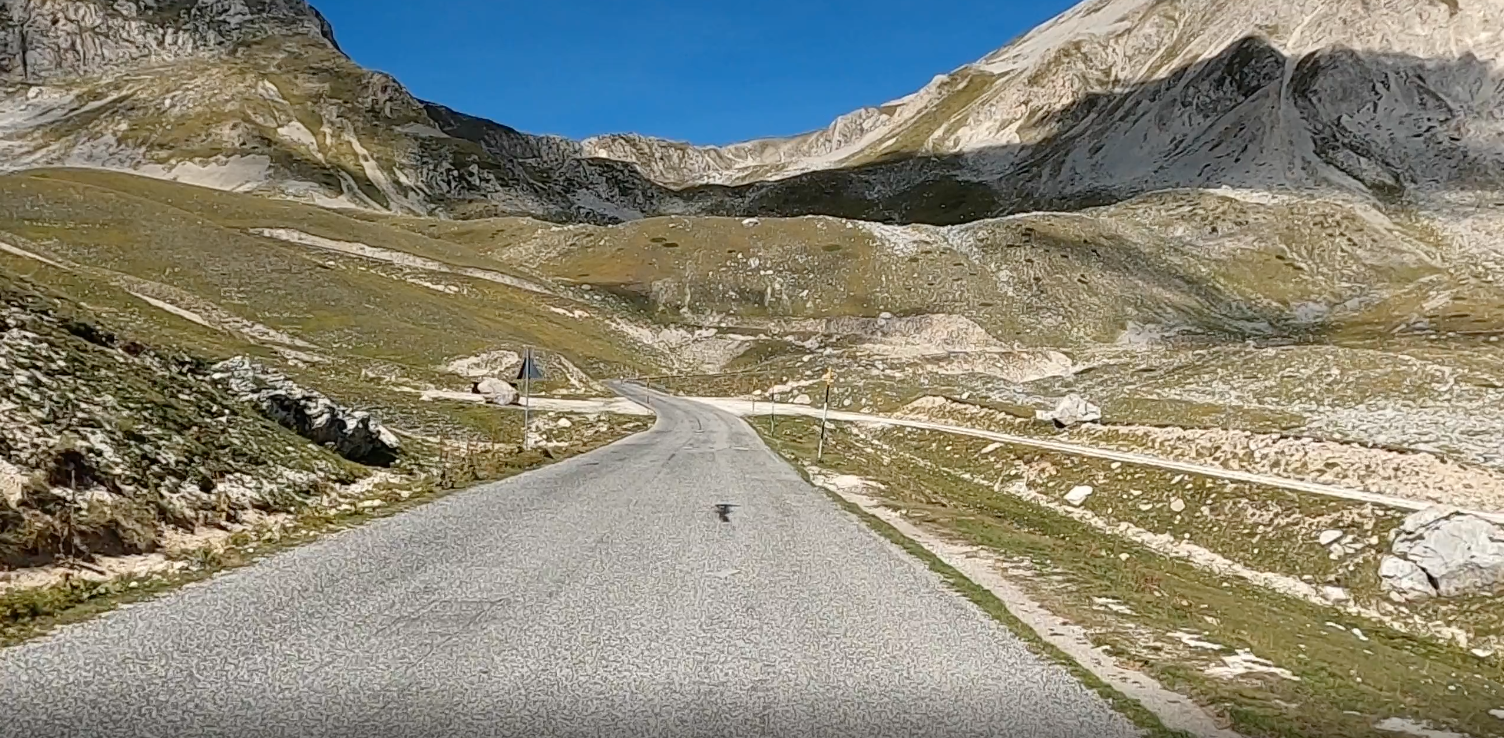 Gran Sasso in Italy - a person riding a bike down a road.