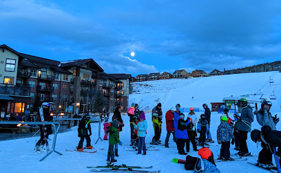 A family and group of people enjoying winter sports at Granby Ranch Ski Resort in Colorado USA with a ski lift in the background.