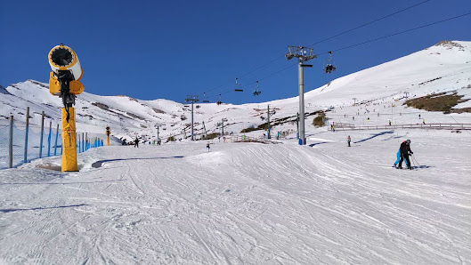 A picturesque view of Alto Campoo ski resort in Cantabria Spain featuring a charming chalet a bustling winter sports scene anchored by a ski lift all surrounded by a crisp winter landscape.