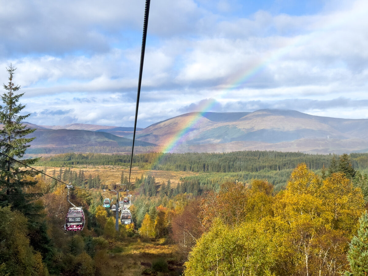 A ski lift at Nevis Range in Scotland on a sunny day, with a chalet and mountain visible in the backdrop of the popular ski resort.