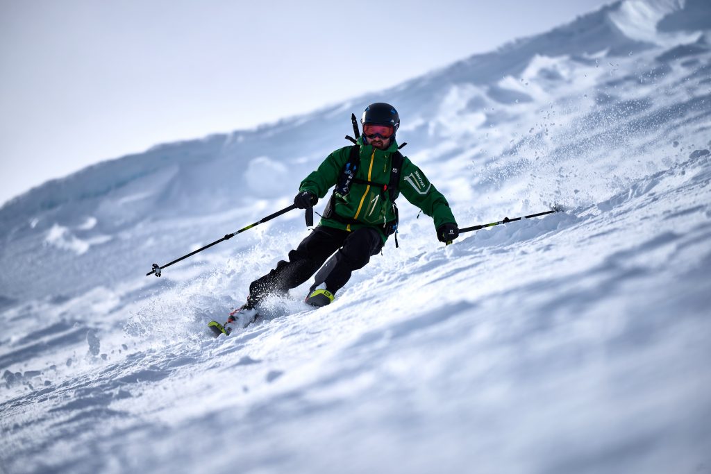 A skier enjoying a winter sports scene at the Nevis Range in the Scottish Highlands, with a quaint chalet in the background.