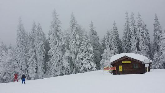 Winter sports enthusiasts enjoying activities at La Dôle | ​Les Tuffes ski resort in France's Bourgogne-Franche-Comté region, surrounded by pristine snowy landscape and a cozy mountain hut.