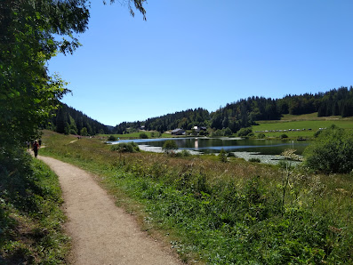 A charming chalet nestles in the tranquil heart of Les Rousses Couvaloup de Crans France. The image captures a serene lake and brilliant sunshine illuminating the day. A mountain bike hints at the region's outdoor activities.