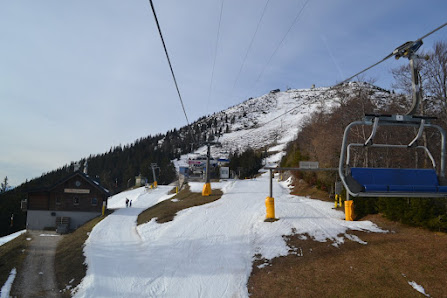 A serene winter scene at Gemeindealpe Mitterbach ski resort in Austria featuring a ski lift ascending snow-covered slopes a cozy challet amid the snow all part of a vibrant winter sports locale.