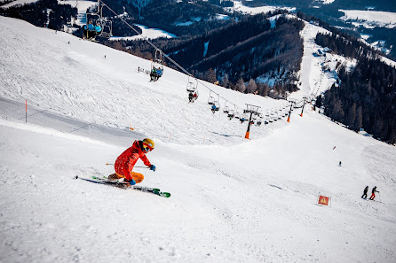 A skier and snowboarder enjoying winter sports on the slopes of Gemeindealpe Mitterbach a ski resort in Lower Austria with a charming chalet in the background.