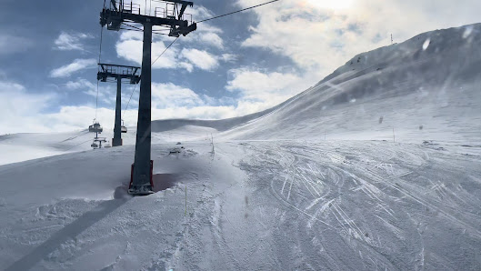 A lively ski resort in Goderdzi, Danisparauli, Adjara, Georgia. A chalet is visible next to the ski lift, which makes its way up the wintery mountainside. A solitary skier creates a dynamic scene of winter sports.