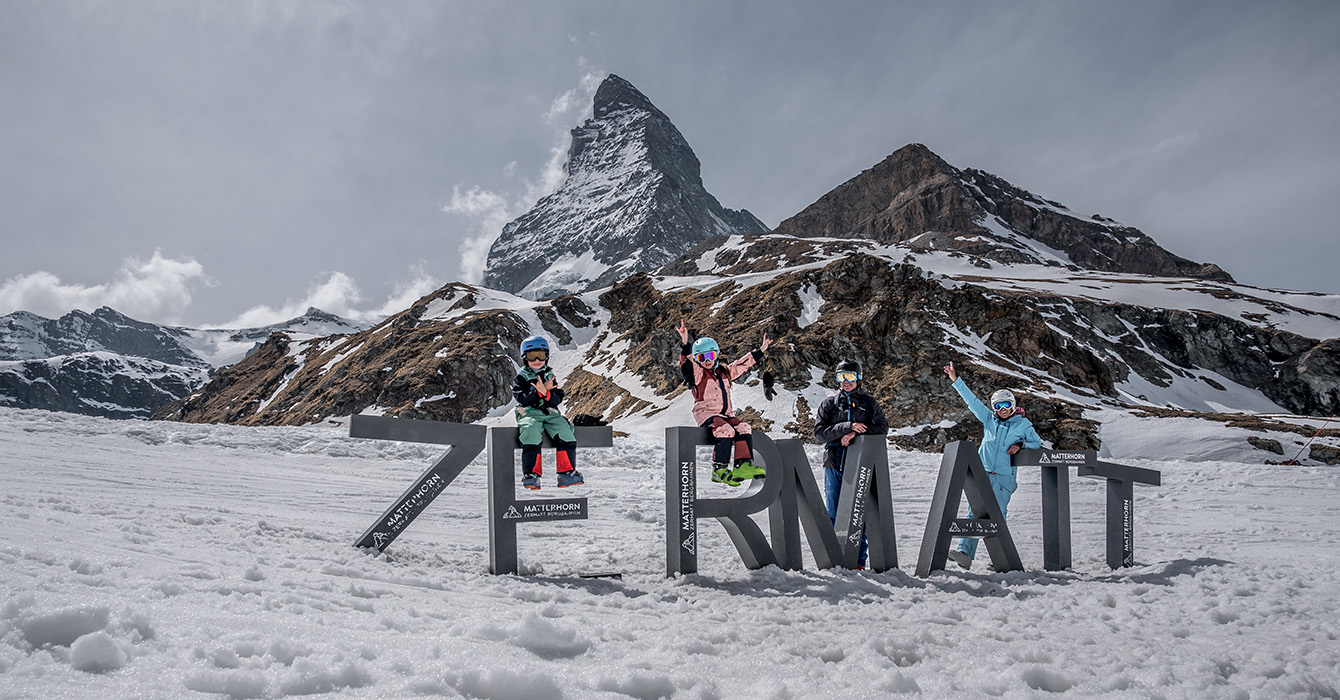 Zermatt Ski Resort in Switzerland - a group of people sitting on a bench in the snow.