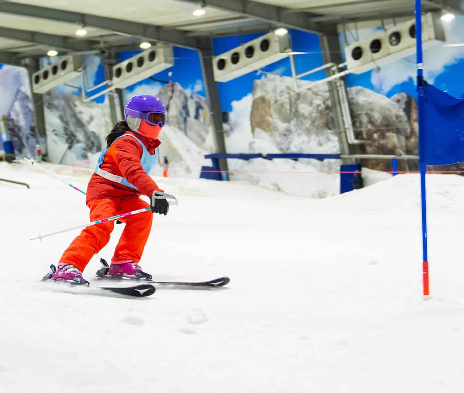 Snowplanet – Silverdale in New Zealand - a person in an orange suit skiing down a slope.