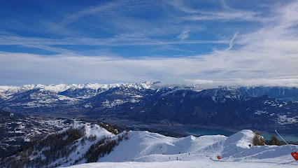 A ski resort in Réallon France featuring a rustic chalet and an active skier. The scene exudes the thrill of winter sports set against an imposing mountain backdrop.