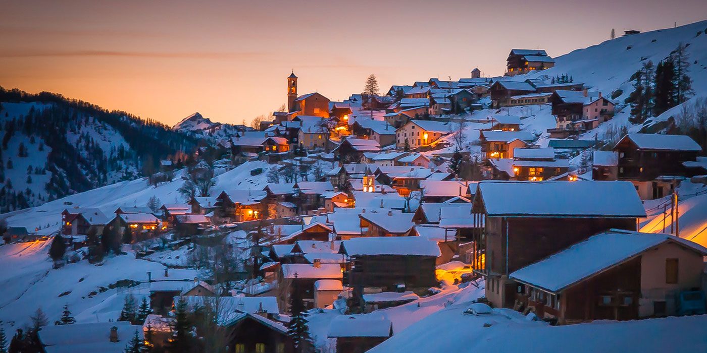 Winter scene at Saint-Véran in France, featuring a charming chalet amidst a bustling ski resort. Surrounded by stunning snowy landscapes, creating an idyllic winter sports setting.