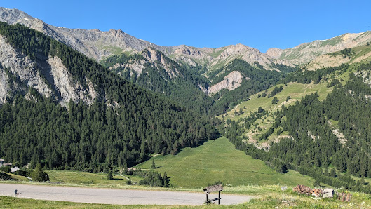 Image of a scenic view in Saint-Véran, France. A chalet is seen against the backdrop of the magnificent mountain range. The surroundings suggest it's a ski resort with a ski lift subtly visible.