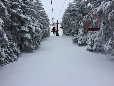 A scenic view of Magic Mountain ski resort in Vermont featuring a ski lift ascending the mountain a skier in action with a charming chalet nearby. The perfect winter sports scene.