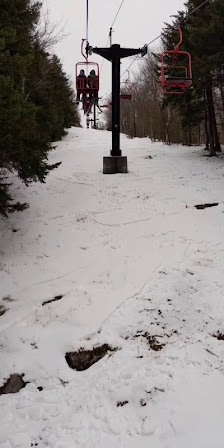 A skier glides down the slopes of Magic Mountain in Londerry Vermont. A ski lift runs up the snowy landscape. This winter sports scene captures the essence of a day at the ski resort.