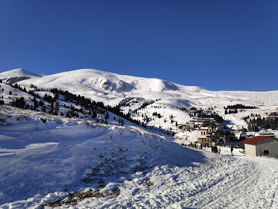Ski resort at Popova Sapka, North Macedonia, featuring a cozy challet amidst a bustling winter sports scene. The landscape is adorned with snow-covered slopes.