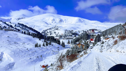 A picturesque view of Popova Sapka ski resort in North Macedonia featuring a charming chalet and a bustling winter sports scene amidst stunning whitewashed scenery.
