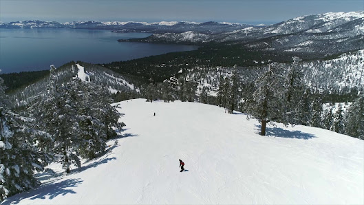 A skier enjoying winter sports at the Diamond Peak Ski Resort in Incline Village, Lake Tahoe, Nevada. Other skiers and a ski lift can be faintly seen in the background.