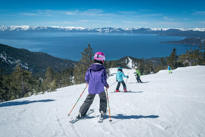A winter sports scene at Diamond Peak in Lake Tahoe, Incline Village, Nevada. A skier is the focus, potentially a part of a family skiing. A ski resort can be seen in the background.