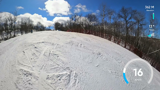 A skier and a snowboarder enjoying a sunny day on the slopes at Alpine Ski Club in The Blue Mountains, Ontario. The ski lift and resort complete this winter sports scene.