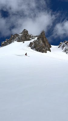 A skier glides down a slope in the scenic ski resort town of Arolla Switzerland. Charming chalets dot the landscape and grand mountains dusted with snow command the backdrop.