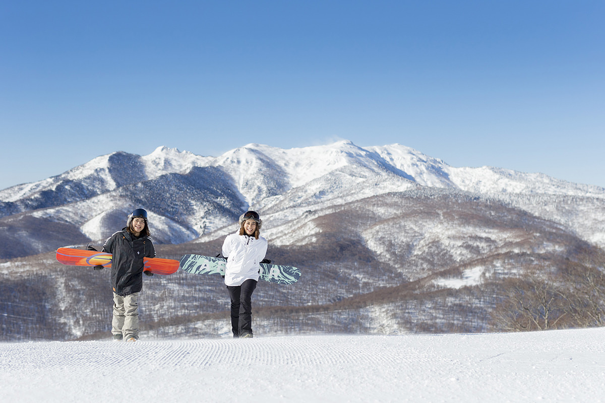 Oze Iwakura in Japan - two people standing on top of a snow covered hill.