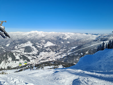 Ski resort in Borsa, Romania. Winter sports enthusiasts, including a skier, enjoy the snowy slopes. A picturesque chalet rests nearby, set against a stunning winter scenery.