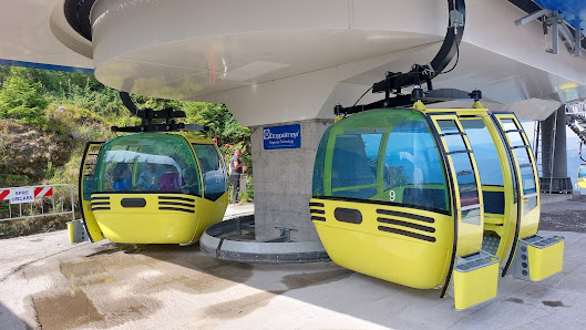 A ski lift cutting through the snowy landscape at Olimpica – Borșa a ski resort in Borsa Maramureș Romania. A snowmobile and a quaint chalet are present with a skier in the distance.