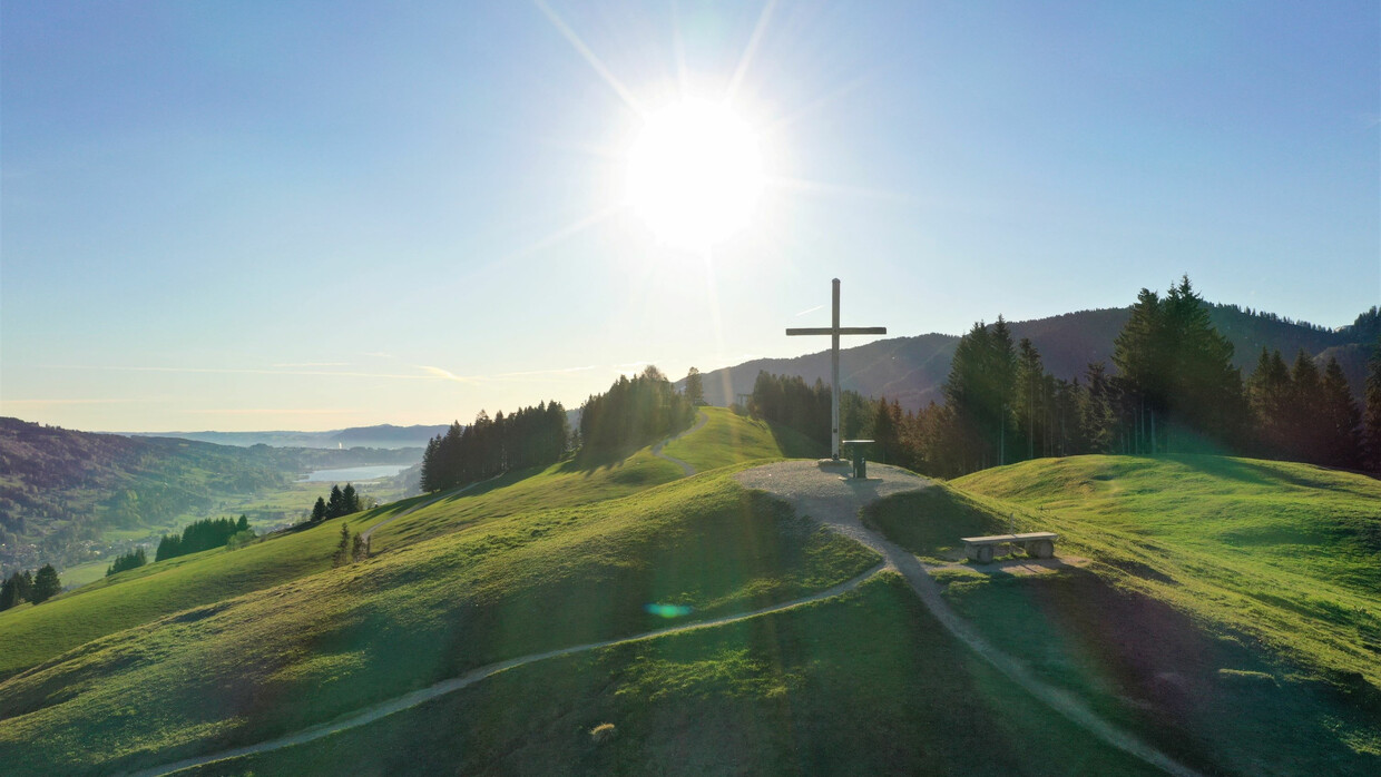 Hündle | Thalkirchdorf in Germany - a cross sitting on top of a green hill.
