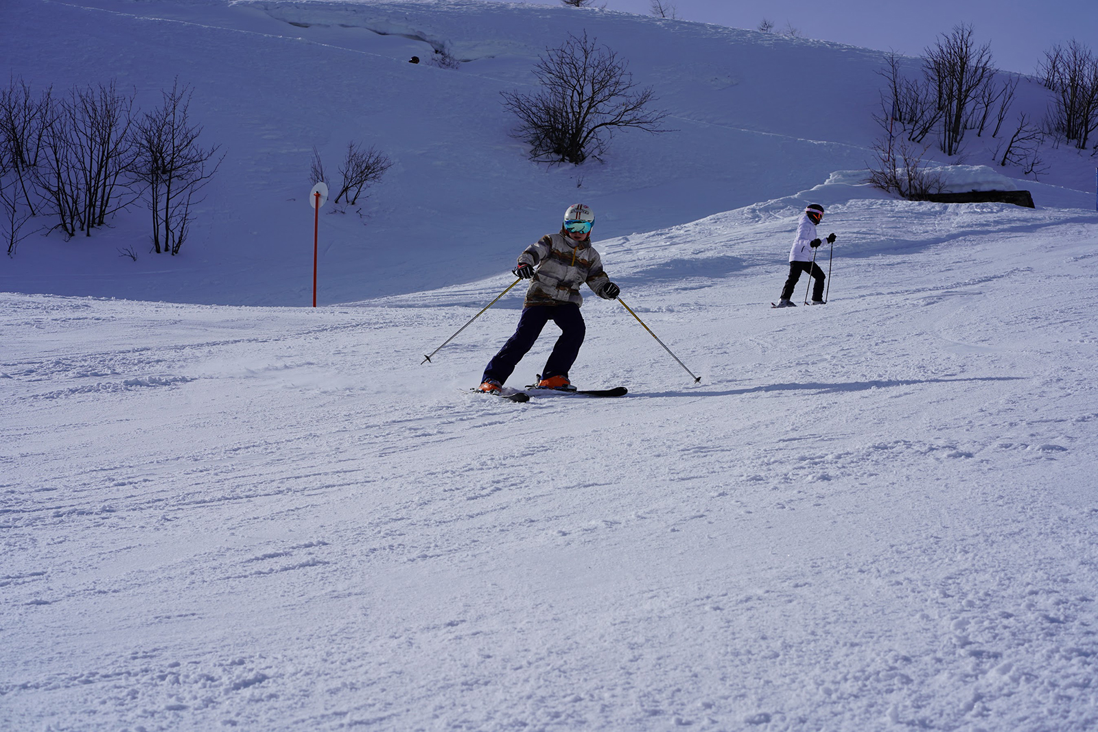 Passo Maniva in Italy - two people are skiing down a snowy hill.