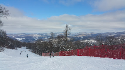Winter sports enthusiasts enjoying the day at Belleayre Mountain ski resort in The Catskills, Highmount, New York, with a charming chalet and stunning snow-covered scenery in the background.