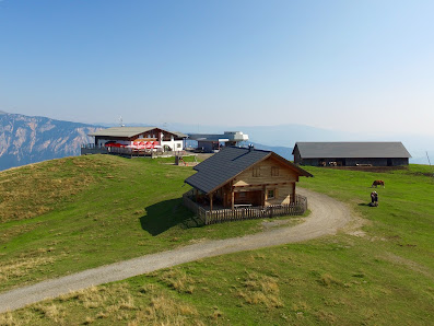 View of Arnoldstein Dreiländereck ski resort in Austria featuring a charming mountain chalet and a winter sports centre amid a picturesque snowy landscape.