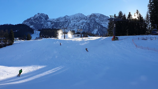 Winter sports scene at Karkogel – Abtenau ski resort in Salzburg, Austria featuring a bustling sports centre, cozy challet and an enthusiastic skier enjoying the snowy slope.