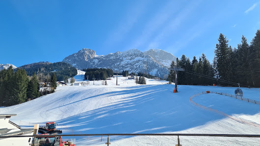 Karkogel – Abtenau, a bustling winter sports centre in Austria. The scene captures a lively ski resort nestled among snow-covered peaks, with a charming chalet in the foreground.