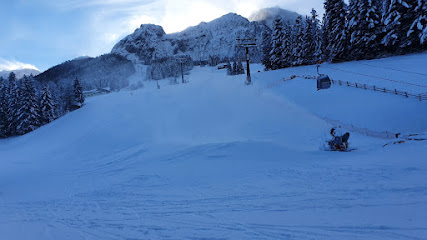 Austrian ski resort of Karkogel – Abtenau featuring a chalet, skiers, enjoying winter sports on the snowy mountain terrain.